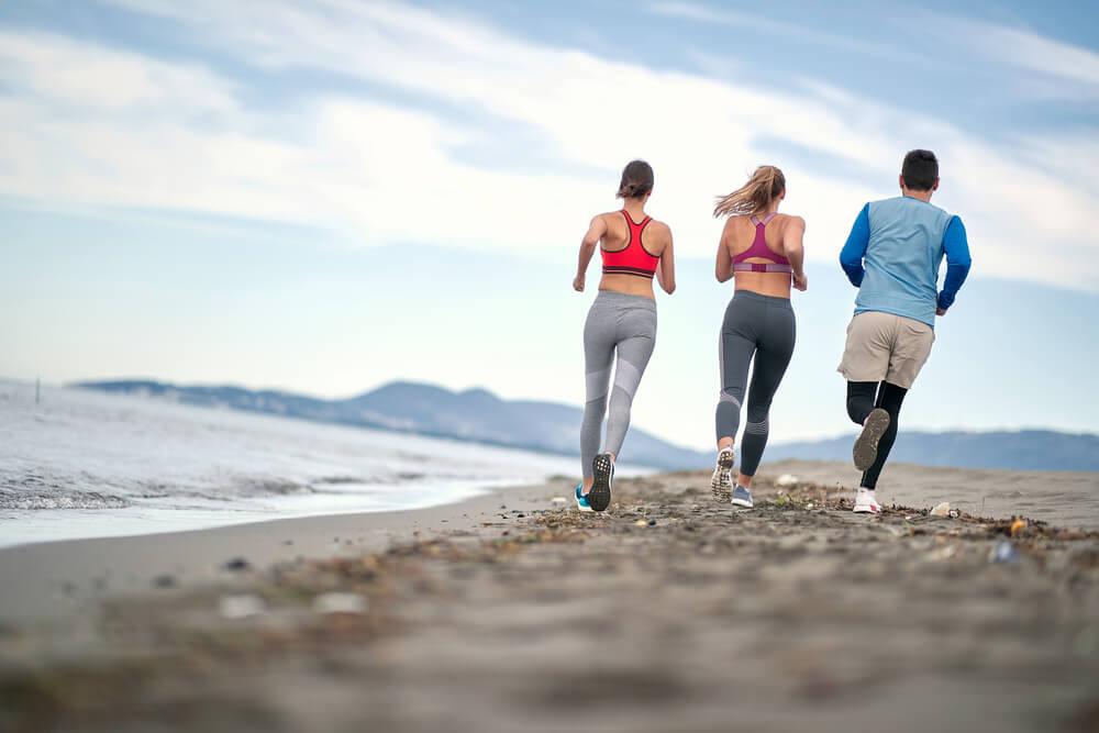 Trojica športovcov beží po pláži